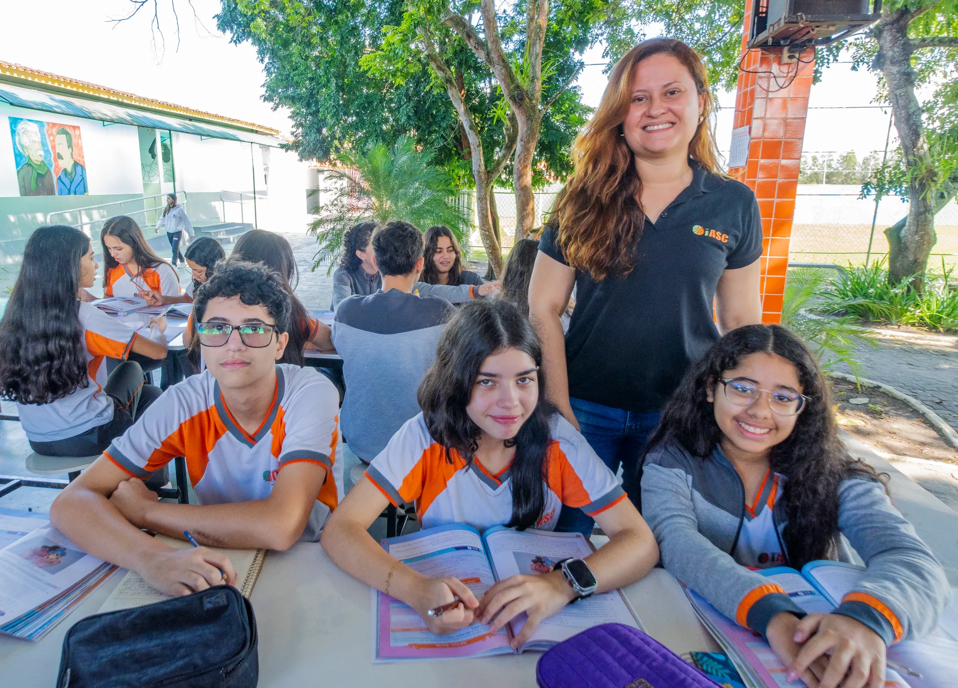 Aluna sorrindo enquanto usa um tablet para estudar